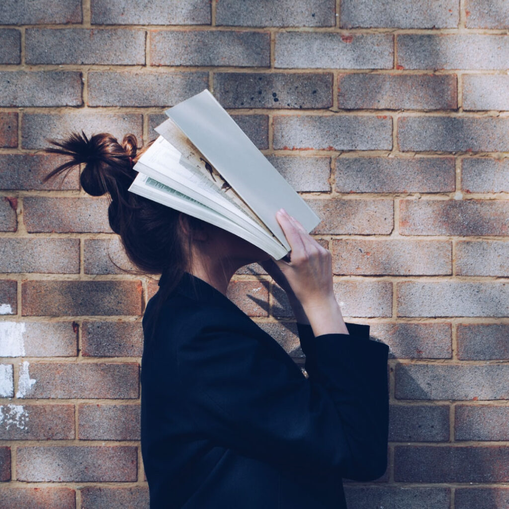 本で顔を覆う女性